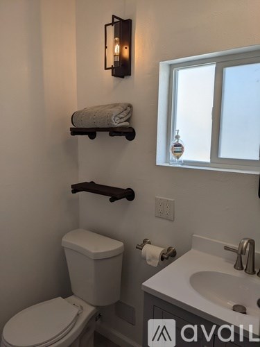 A white toilet with a towel on the shelf above it.