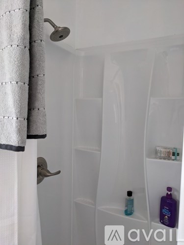 A white shower stall with a towel hanging on the door and a shower head.