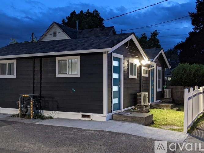 A small house with a dark grey exterior and a blue door is shown.