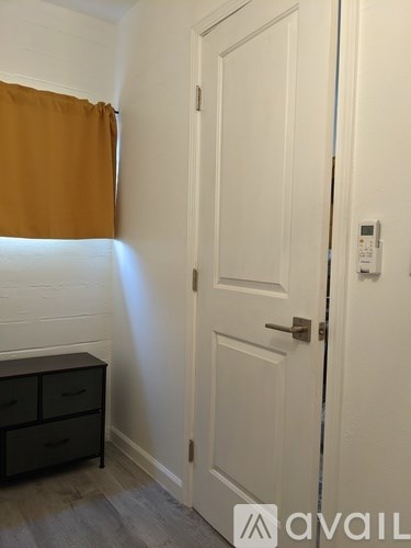 A white door with a brown curtain to the left and a black cabinet below it.