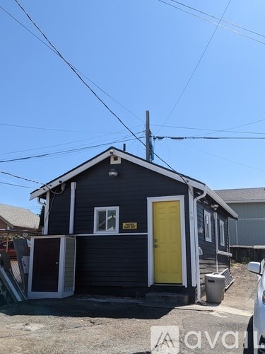 A small house with a yellow door is situated on a street.