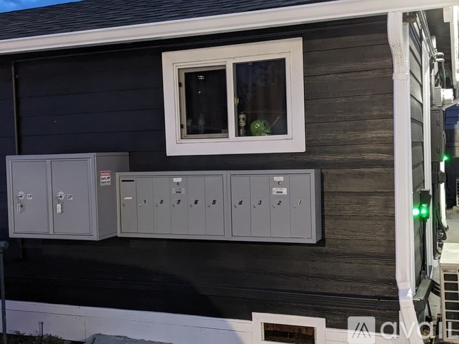 A black house with a white window and grey electrical boxes.