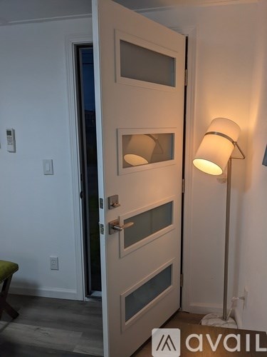 A white door with a glass panel and a white lamp on the side.