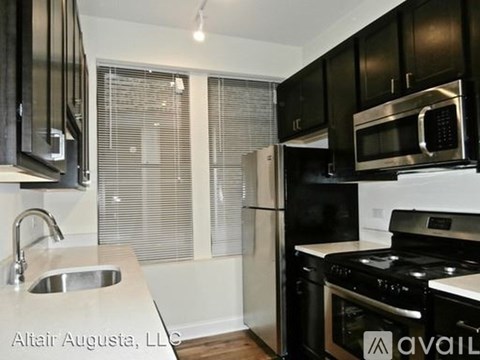 A modern kitchen with black cabinets and stainless steel appliances.