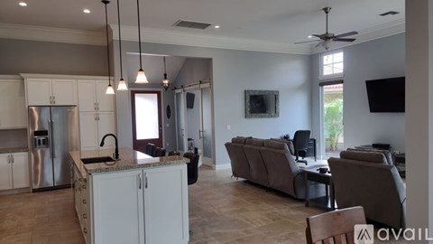 A modern kitchen with a large island and a living room with a couch and chairs.