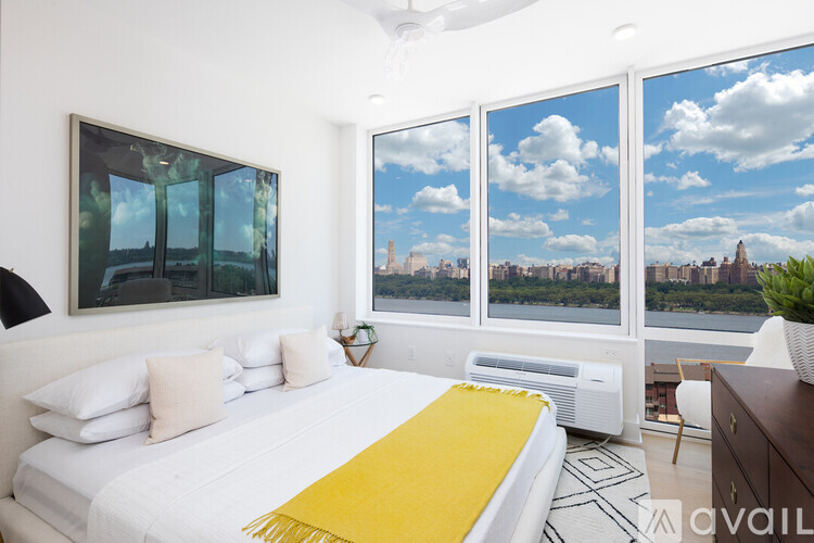 A bedroom with a large bed and a view of the city through the windows.