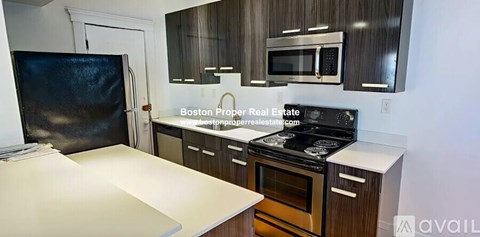 A kitchen with a black refrigerator and wooden cabinets.