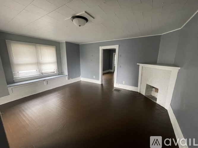 A room with a fireplace and a window with blinds.
