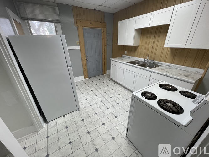 A kitchen with a white fridge, white cabinets, and a white stove top oven.