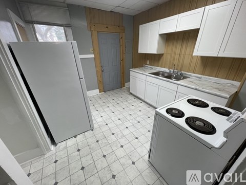 A kitchen with a white fridge, white cabinets, and a white stove top oven.