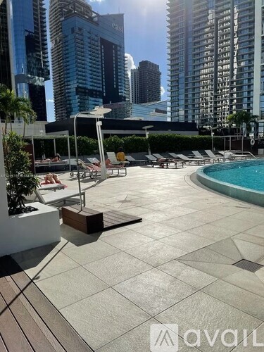 A pool area with a sun lounger and a table with a white umbrella.