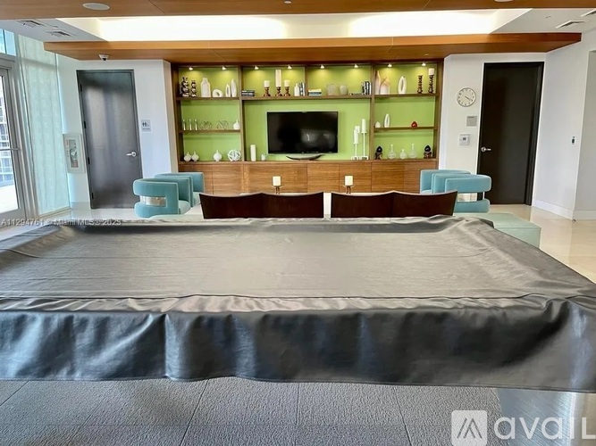 A bedroom with a large bed and a green shelf above the television.