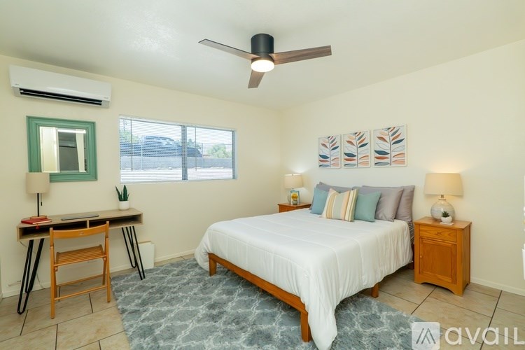 A bedroom with a bed, desk, and window.