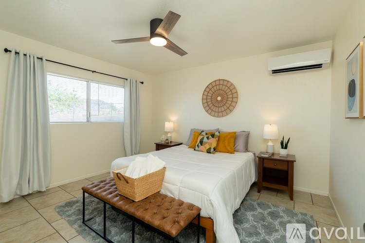 A bedroom with a large bed, a ceiling fan, and a window with curtains.