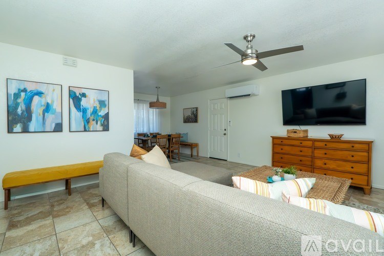 A living room with a couch, a television, and a ceiling fan.
