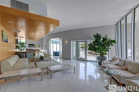 A spacious living room with a white sofa set and a glass table.