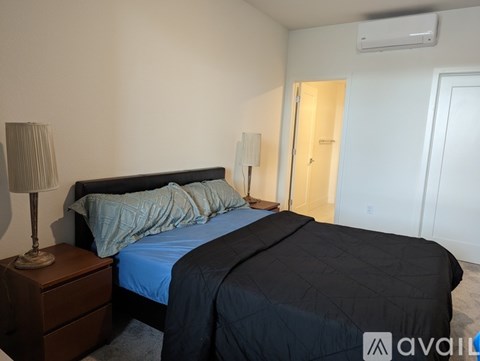 A bedroom with a bed, nightstand, and lamp.