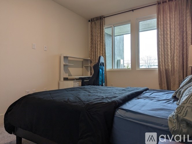 A bedroom with a bed, desk, and window.