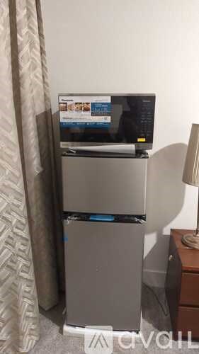 A small refrigerator with a computer monitor on top.