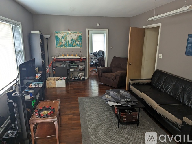 A living room with a black couch, a coffee table, and a TV.