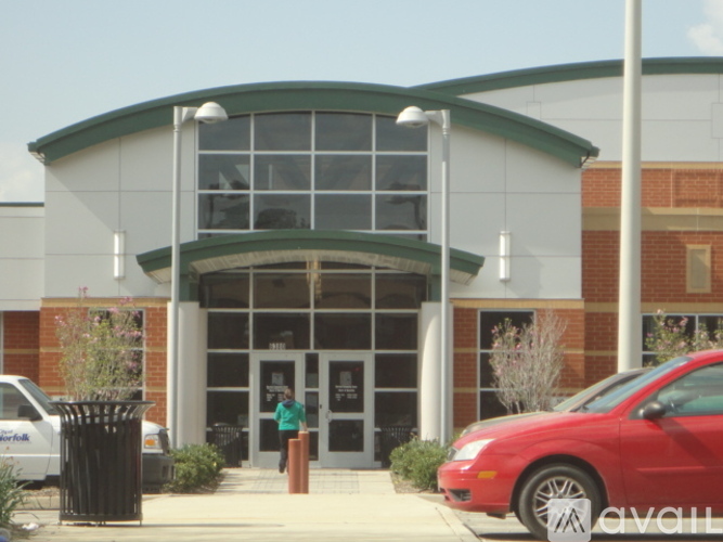 A red car is parked in front of a building with a green roof.