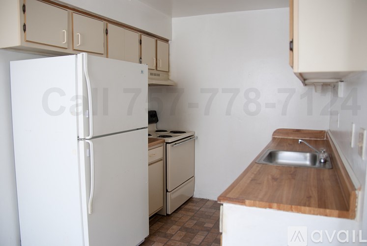 A kitchen with a white refrigerator, sink, and cabinets.