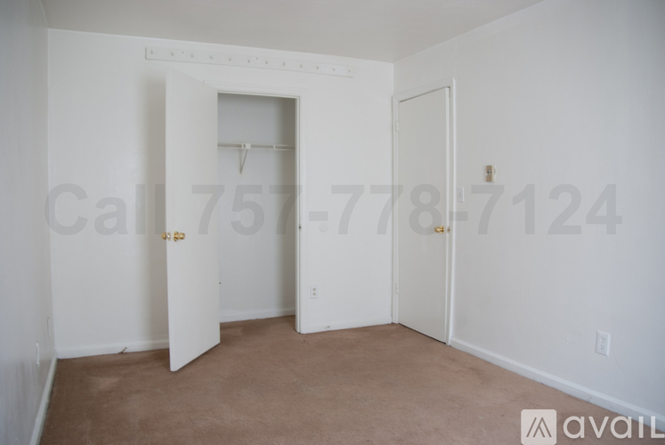 A room with a carpeted floor and three doors, one of which is open.