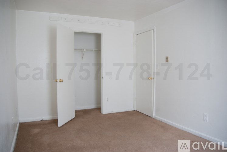 A room with a carpeted floor and three doors, one of which is open.