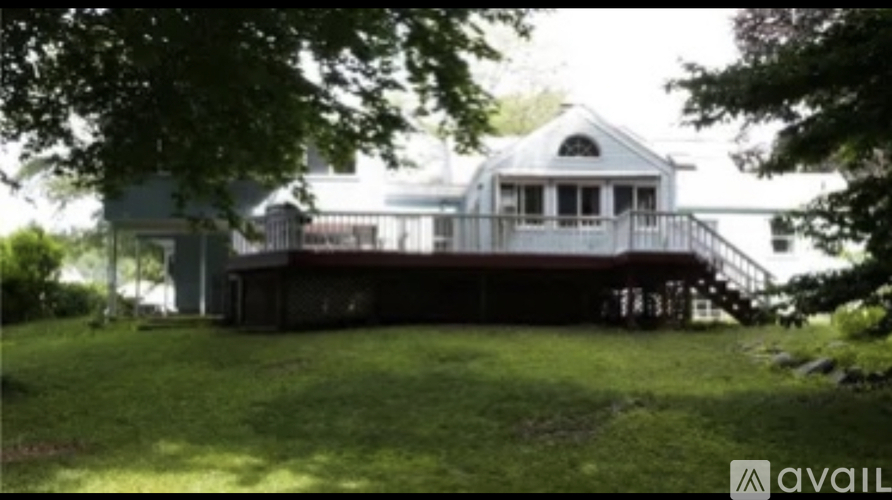 A house with a deck and a tree in front.