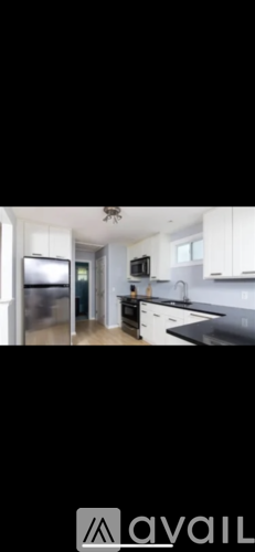 A kitchen with white cabinets and a black countertop.