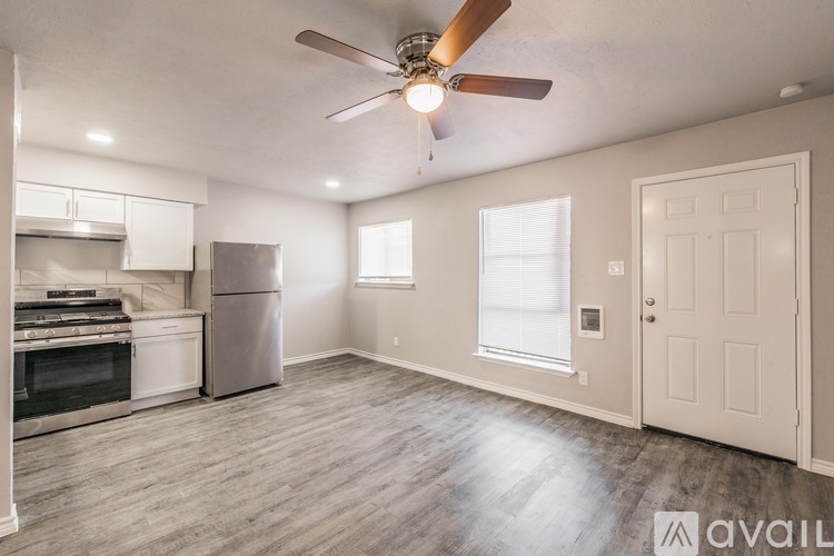 A spacious kitchen with a fan and a refrigerator.