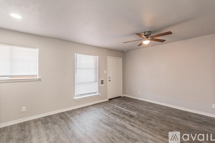 A room with a ceiling fan and light, two windows, and a door.