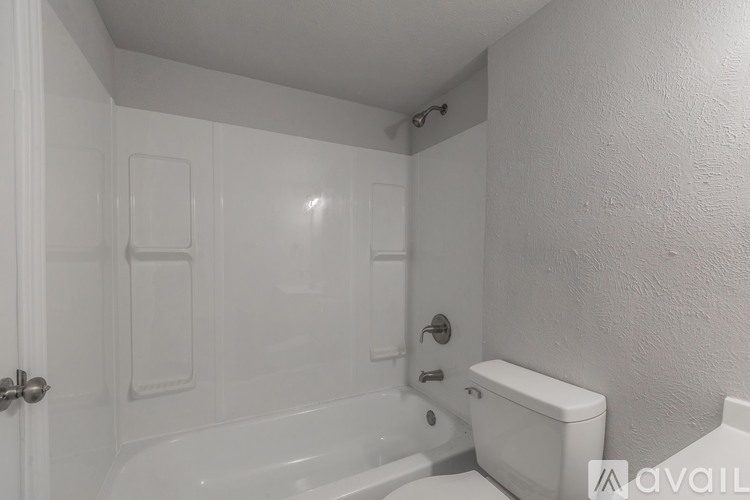 A white bathroom with a toilet, tub, and shower.