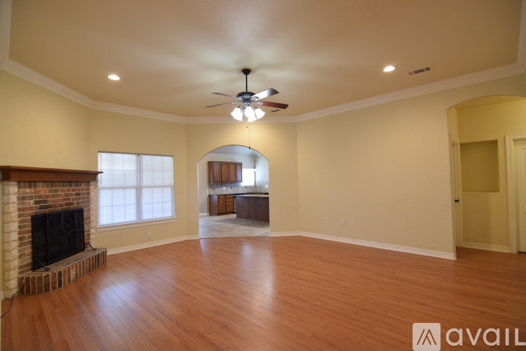 A spacious living room with a fireplace and a ceiling fan.