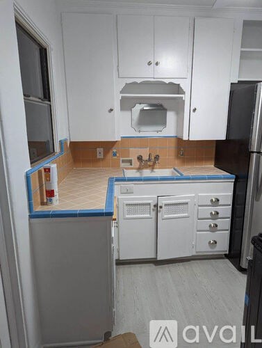 A kitchen with white cabinets and a black refrigerator.