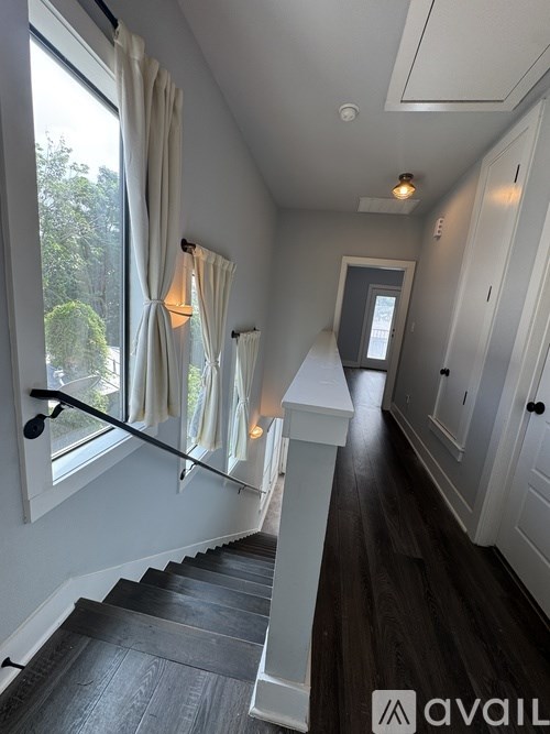 A hallway with a staircase leading to a door at the end.