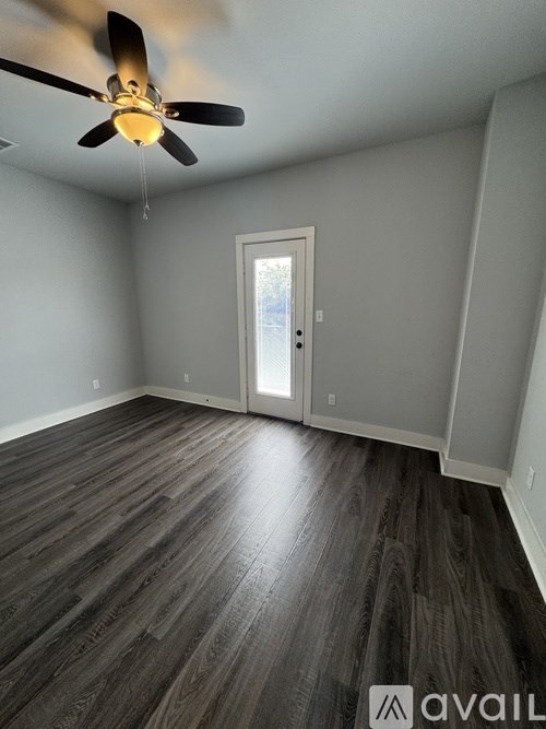 A room with a ceiling fan and wooden flooring.