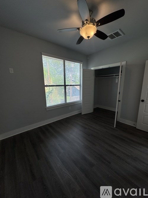 A room with a ceiling fan and a window with blinds.