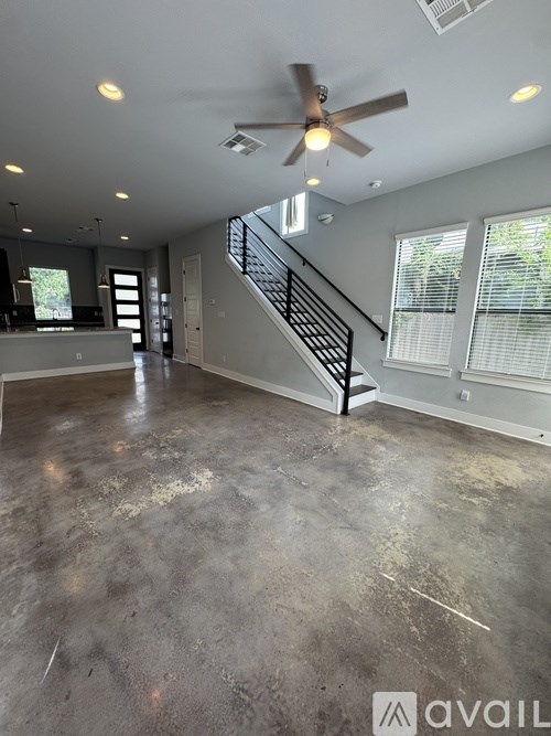 A spacious room with a concrete floor and a staircase leading to the upper level.