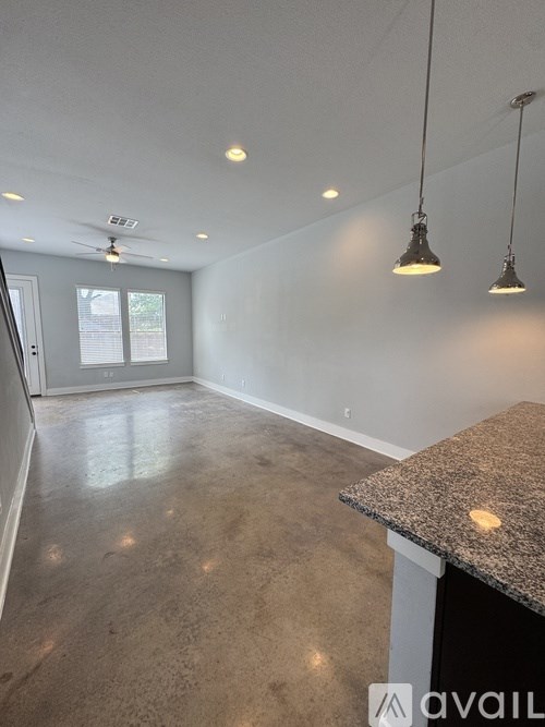 A spacious room with a granite countertop and pendant lights.