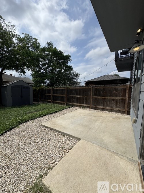 A backyard with a gravel pathway leading to a wooden fence.