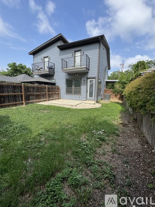 A house with a balcony and a small garden in front.