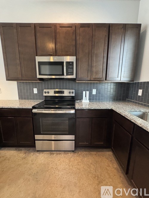 A kitchen with dark brown cabinets and a stainless steel stove.