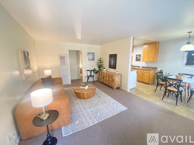 A living room with a couch, a table, and a dining area in the background.