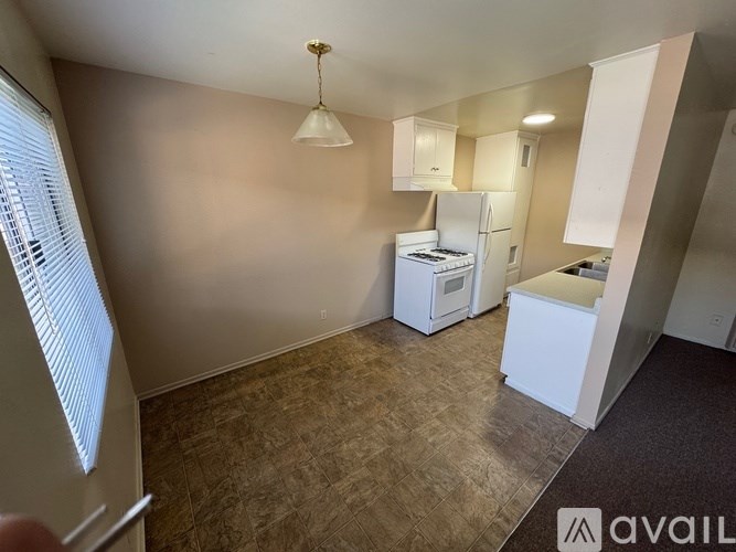 A kitchen area with a refrigerator, stove, and cabinets.