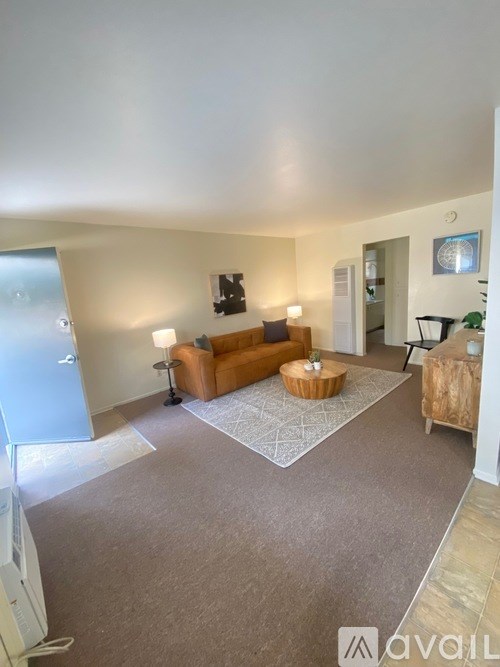 A living room with a brown sofa and a rug.