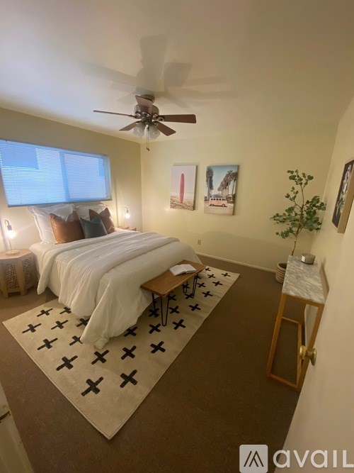 A bedroom with a bed, a ceiling fan, and a rug with black crosses.