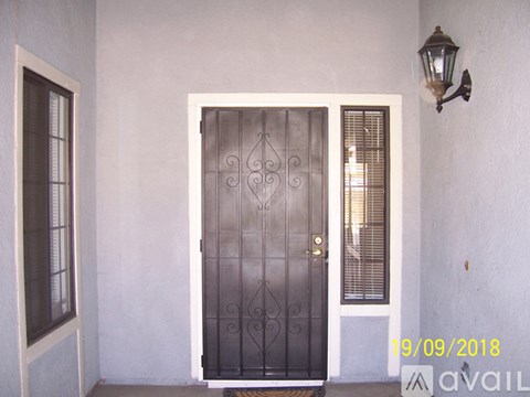 A black wrought iron door with a gold handle is set in a white wall.