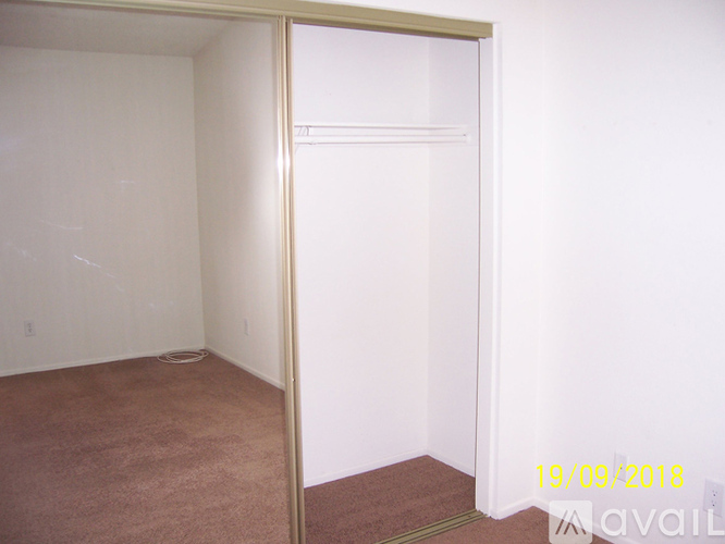 A room with a carpeted floor and a white wall with a doorway leading to another room.