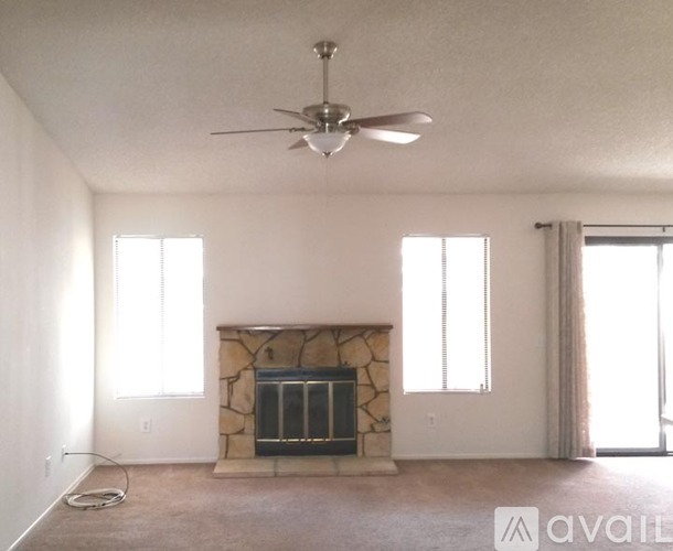 A living room with a fireplace and a ceiling fan.